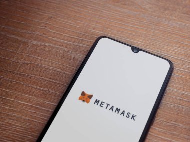 Lod, Israel - 16 Temmuz 2023: MetaMaske uygulaması ahşap arka planda akıllı telefondan çalıştırma ekranı. Üst görünüm düzlüğü kopyalama alanı ile yatıyordu.