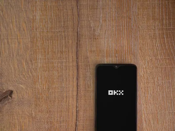 ロッジ イスラエル 2023 木の背景にスマートフォン上でOkxアプリの起動画面 コピースペース付きトップビューフラットレイ ロイヤリティフリーのストック写真