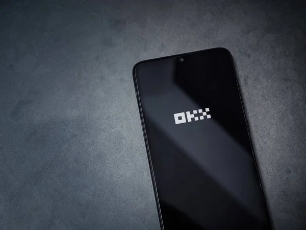 ロッジ イスラエル 2023 ダークマーブルストーンバックグラウンドでスマートフォン上でOkxアプリの起動画面 コピースペース付きトップビューフラットレイ ストック画像