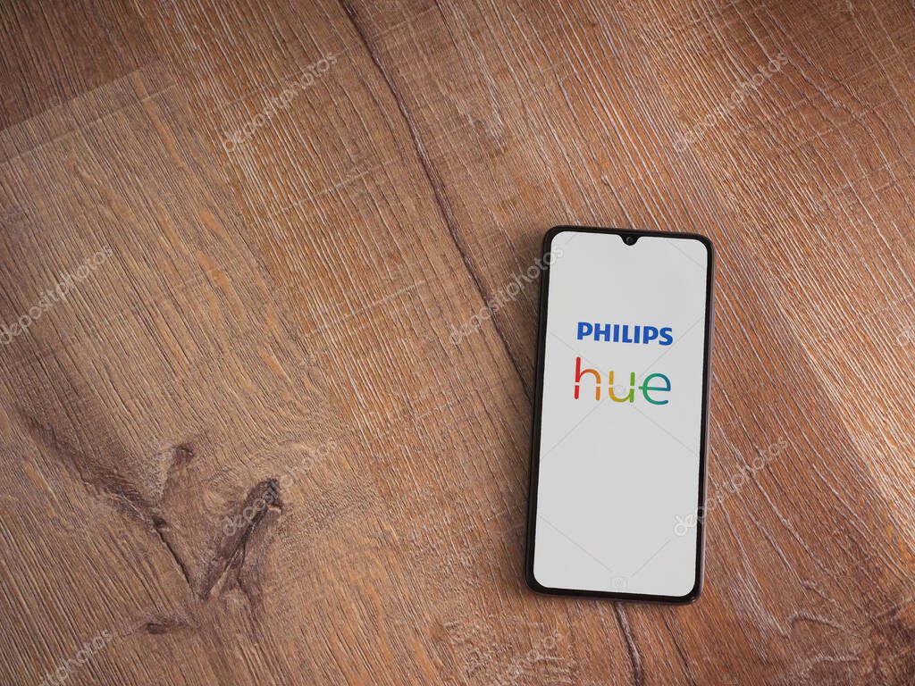 Lod, Israel - July 16,2023: Philips Hue app launch screen on smartphone on wooden background. Top view flat lay with copy space.