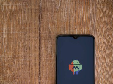Lod, Israel - 16 Temmuz 2023: Makrodroid uygulama ekranı ahşap arka planda akıllı telefondan çalıştırıldı. Üst görünüm düzlüğü kopyalama alanı ile yatıyordu.