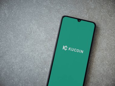Lod, Israel - 16 Temmuz 2023: KuCoin uygulaması seramik taş zemin üzerinde akıllı telefondan fırlatma ekranı. Üst görünüm düzlüğü kopyalama alanı ile yatıyordu.