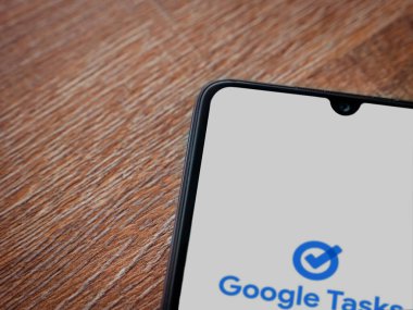 Lod, Israel - 16 Temmuz 2023: Google Görev uygulaması tahta arka planda akıllı telefondan çalıştırma ekranı. Üst görünüm düzlüğü kopyalama alanı ile yatıyordu.