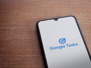 Lod, Israel - 16 Temmuz 2023: Google Görev uygulaması tahta arka planda akıllı telefondan çalıştırma ekranı. Üst görünüm düzlüğü kopyalama alanı ile yatıyordu.