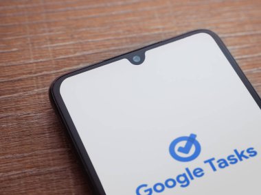 Lod, Israel - 16 Temmuz 2023: Google Görev uygulaması tahta arka planda akıllı telefondan çalıştırma ekranı. Üst görünüm düzlüğü kopyalama alanı ile yatıyordu.