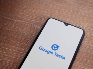 Lod, Israel - 16 Temmuz 2023: Google Görev uygulaması tahta arka planda akıllı telefondan çalıştırma ekranı. Üst görünüm düzlüğü kopyalama alanı ile yatıyordu.