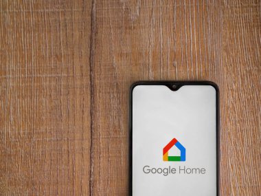 Lod, Israel - 16 Temmuz 2023: Google Home uygulama ekranı ahşap arka planda akıllı telefon. Üst görünüm düzlüğü kopyalama alanı ile yatıyordu.