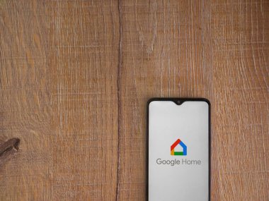 Lod, Israel - 16 Temmuz 2023: Google Home uygulama ekranı ahşap arka planda akıllı telefon. Üst görünüm düzlüğü kopyalama alanı ile yatıyordu.