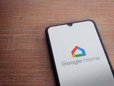 Lod, Israel - 16 Temmuz 2023: Google Home uygulama ekranı ahşap arka planda akıllı telefon. Üst görünüm düzlüğü kopyalama alanı ile yatıyordu.