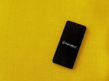 Lod, Israel - 16 Temmuz 2023: Uçuş İzleyici Uygulaması uygulaması sarı kumaş arka planda akıllı telefondan kalkış ekranı. Üst görünüm düzlüğü kopyalama alanı ile yatıyordu.
