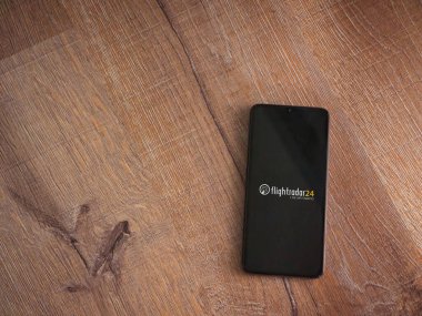 Lod, İsrail - 16 Temmuz 2023: Uçuş Takip 24 uygulama ekranı ahşap arka planda akıllı telefon. Üst görünüm düzlüğü kopyalama alanı ile yatıyordu.