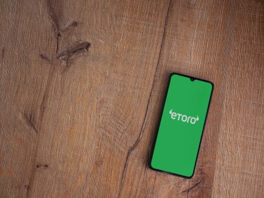 Lod, Israel - 16 Temmuz 2023: eToro uygulama ekranı ahşap arka planda akıllı telefon. Üst görünüm düzlüğü kopyalama alanı ile yatıyordu.