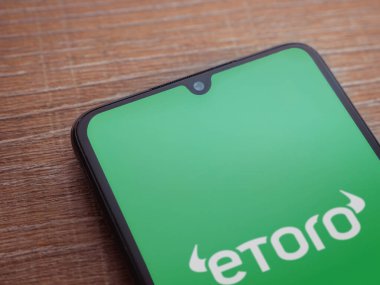 Lod, Israel - 16 Temmuz 2023: eToro uygulama ekranı ahşap arka planda akıllı telefon. Üst görünüm düzlüğü kopyalama alanı ile yatıyordu.