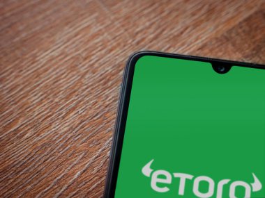 Lod, Israel - 16 Temmuz 2023: eToro uygulama ekranı ahşap arka planda akıllı telefon. Üst görünüm düzlüğü kopyalama alanı ile yatıyordu.