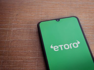 Lod, Israel - 16 Temmuz 2023: eToro uygulama ekranı ahşap arka planda akıllı telefon. Üst görünüm düzlüğü kopyalama alanı ile yatıyordu.