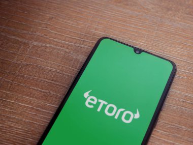 Lod, Israel - 16 Temmuz 2023: eToro uygulama ekranı ahşap arka planda akıllı telefon. Üst görünüm düzlüğü kopyalama alanı ile yatıyordu.
