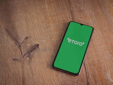 Lod, Israel - 16 Temmuz 2023: eToro uygulama ekranı ahşap arka planda akıllı telefon. Üst görünüm düzlüğü kopyalama alanı ile yatıyordu.