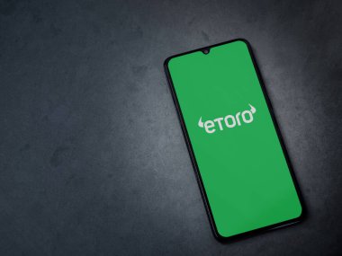 Lod, Israel - 16 Temmuz 2023: eToro uygulaması koyu mermer taşlı arka planda akıllı telefondan kalkış ekranı. Üst görünüm düzlüğü kopyalama alanı ile yatıyordu.