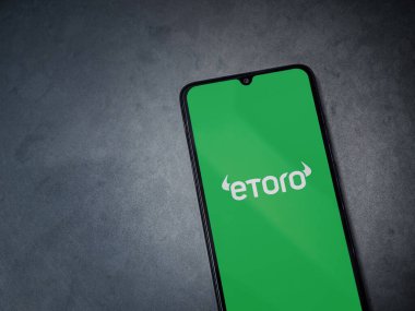 Lod, Israel - 16 Temmuz 2023: eToro uygulaması koyu mermer taşlı arka planda akıllı telefondan kalkış ekranı. Üst görünüm düzlüğü kopyalama alanı ile yatıyordu.