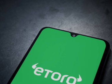 Lod, Israel - 16 Temmuz 2023: eToro uygulaması koyu mermer taşlı arka planda akıllı telefondan kalkış ekranı. Üst görünüm düzlüğü kopyalama alanı ile yatıyordu.