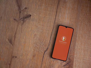 Lod, Israel - 16 Temmuz 2023: DuckDuckGo Özel Tarayıcı uygulama ekranı ahşap arka planda akıllı telefon. Üst görünüm düzlüğü kopyalama alanı ile yatıyordu.