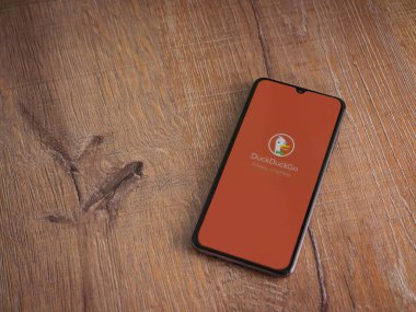 Lod, Israel - 16 Temmuz 2023: DuckDuckGo Özel Tarayıcı uygulama ekranı ahşap arka planda akıllı telefon. Üst görünüm düzlüğü kopyalama alanı ile yatıyordu.
