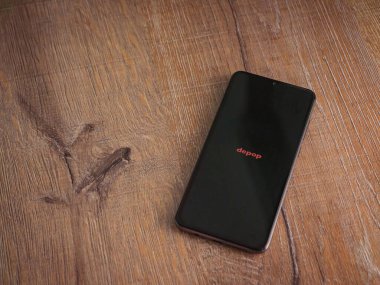 Lod, Israel - 16 Temmuz 2023: Ahşap arka planda akıllı telefondan Depop uygulaması fırlatma ekranı. Üst görünüm düzlüğü kopyalama alanı ile yatıyordu.