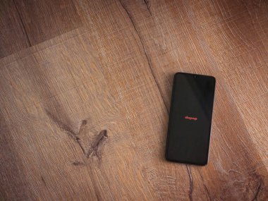 Lod, Israel - 16 Temmuz 2023: Ahşap arka planda akıllı telefondan Depop uygulaması fırlatma ekranı. Üst görünüm düzlüğü kopyalama alanı ile yatıyordu.