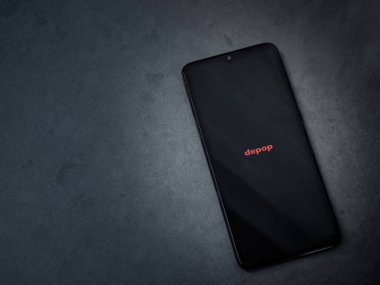 Lod, Israel - 16 Temmuz 2023: Koyu mermer taşlı arka planda akıllı telefondan Depop uygulaması fırlatma ekranı. Üst görünüm düzlüğü kopyalama alanı ile yatıyordu.