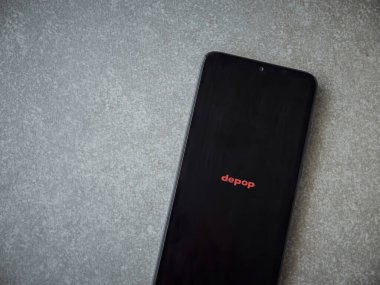 Lod, Israel - 16 Temmuz 2023: Seramik taş zemin üzerinde akıllı telefondan Depop uygulaması fırlatma ekranı. Üst görünüm düzlüğü kopyalama alanı ile yatıyordu.