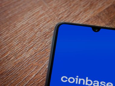 Lod, Israel - 16 Temmuz 2023: Ahşap zemin üzerinde akıllı telefon ile sikke bazlı uygulama fırlatma ekranı. Üst görünüm düzlüğü kopyalama alanı ile yatıyordu.