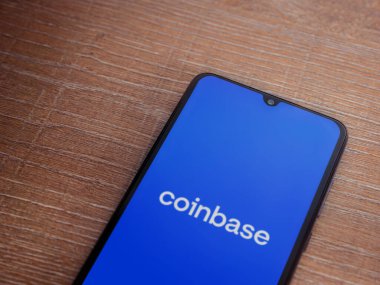 Lod, Israel - 16 Temmuz 2023: Ahşap zemin üzerinde akıllı telefon ile sikke bazlı uygulama fırlatma ekranı. Üst görünüm düzlüğü kopyalama alanı ile yatıyordu.