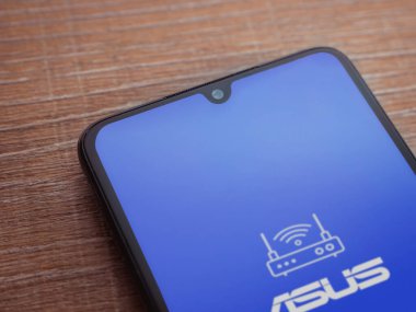 Lod, Israel - 16 Temmuz 2023: ASUS Router uygulama ekranı ahşap arka planda akıllı telefon. Üst görünüm düzlüğü kopyalama alanı ile yatıyordu.