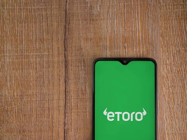 Lod, Israel - 16 Temmuz 2023: eToro uygulama ekranı ahşap arka planda akıllı telefon. Üst görünüm düzlüğü kopyalama alanı ile yatıyordu.