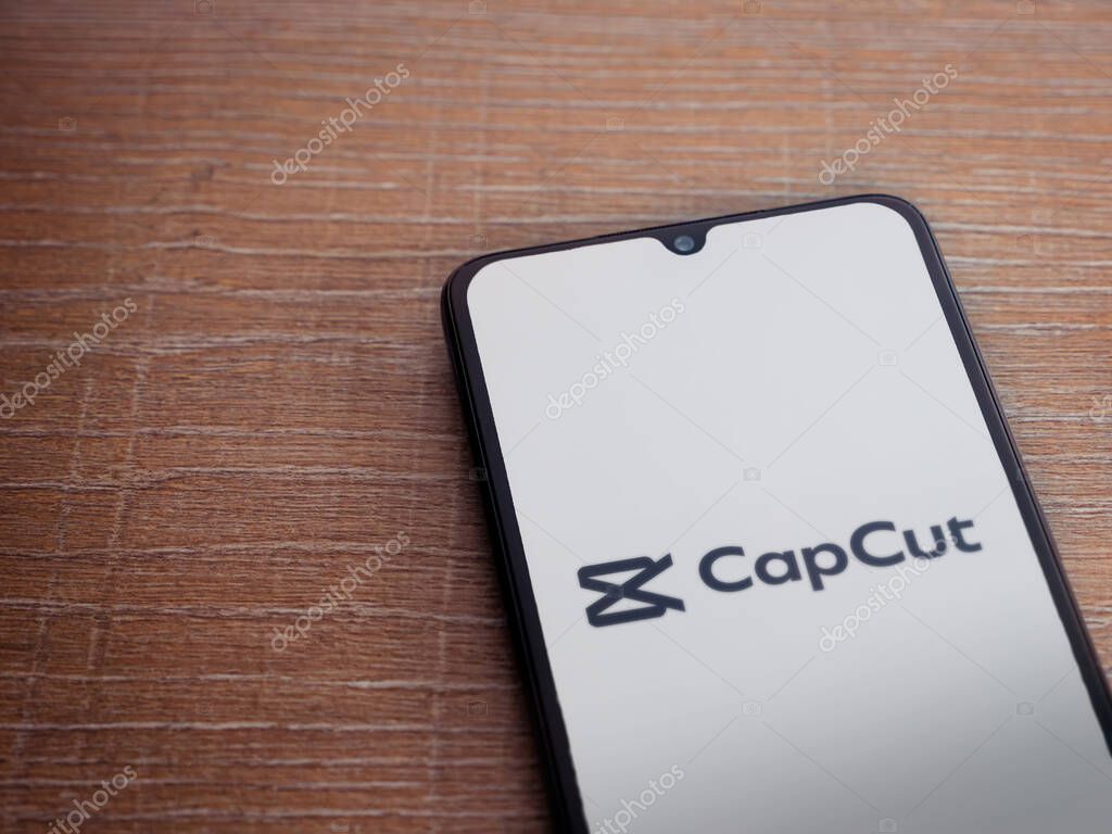 Lod, Israel - July 16,2023: CapCut app launch screen on smartphone on wooden background.. Top view flat lay with copy space.