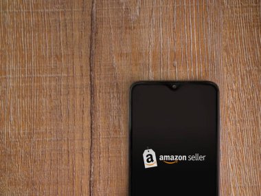 Lod, Israel - 16 Temmuz 2023: Amazon Seller uygulama ekranı ahşap arka planda akıllı telefondan çalıştırılıyor. Üst görünüm düzlüğü kopyalama alanı ile yatıyordu.