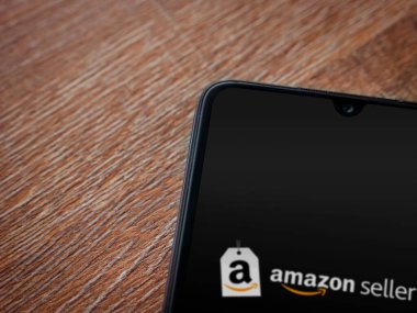 Lod, Israel - 16 Temmuz 2023: Amazon Seller uygulama ekranı ahşap arka planda akıllı telefondan çalıştırılıyor. Üst görünüm düzlüğü kopyalama alanı ile yatıyordu.