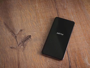 Lod, Israel - 16 Temmuz 2023: AirTM uygulama ekranı ahşap arka planda akıllı telefon. Üst görünüm düzlüğü kopyalama alanı ile yatıyordu.
