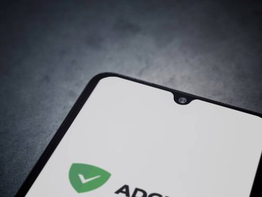 Lod, Israel - 16 Temmuz 2023: AdGuard uygulaması koyu mermer taşlı arka planda akıllı telefondan çalıştırma ekranı. Üst görünüm düzlüğü kopyalama alanı ile yatıyordu.