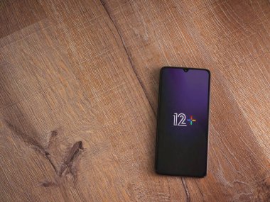 Lod, Israel - 16 Temmuz 2023: 12 + uygulama ekranı ahşap zemin üzerinde akıllı telefon. Üst görünüm düzlüğü kopyalama alanı ile yatıyordu.