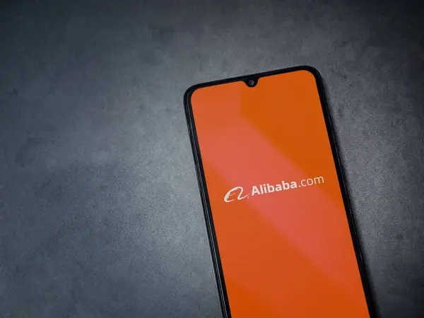 Lod, Israel - 16 Temmuz 2023: Alibaba.com uygulaması koyu mermer taşlı arka planda akıllı telefondan çalıştırma ekranı. Üst görünüm düzlüğü kopyalama alanı ile yatıyordu.