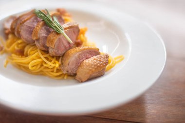 Beyaz tabakta spagetti ve ızgara ördek.