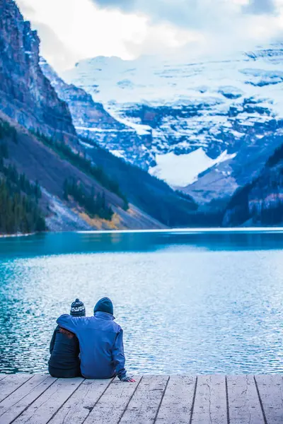 Birkaç genç turist gölde oturuyor ve gün batımında Kanada 'nın güzel dağ manzarasını izliyorlar. Banff, alberta, Kanada