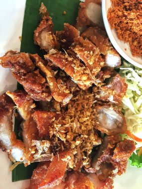 Beyaz bir tabakta muz yaprağında kızarmış domuz eti..