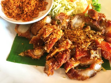 Beyaz bir tabakta muz yaprağında kızarmış domuz eti..