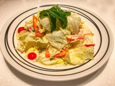 Beyaz tabakta baharatlı ton balığı salatası..