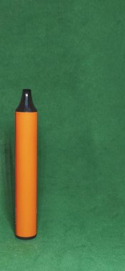 orange electronic cigarette for smoking light smoke, on a green background