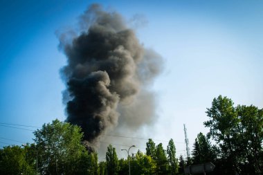 Bir orman yangınını söndürmek için suyu şarj eden acil durum helikopteri mavi gökyüzüne doğru yoğun siyah duman yükseliyor. Ateşten duman çıkıyor. Felaket! Yüksek kalite fotoğraf
