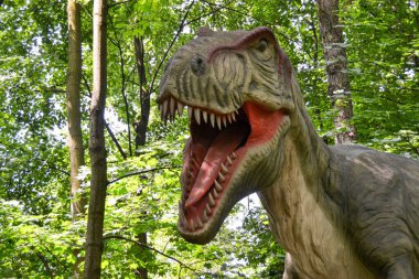 Jurasik dünyadan bir sahnede bir dinazor gösteriliyor. Parktaki dinozor modeli. Dev Tyrannosaurus parktaki bir sergide.