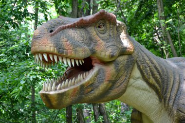 Jurasik dünyadan bir sahnede bir dinazor gösteriliyor. Parktaki dinozor modeli. Dev Tyrannosaurus parktaki bir sergide.